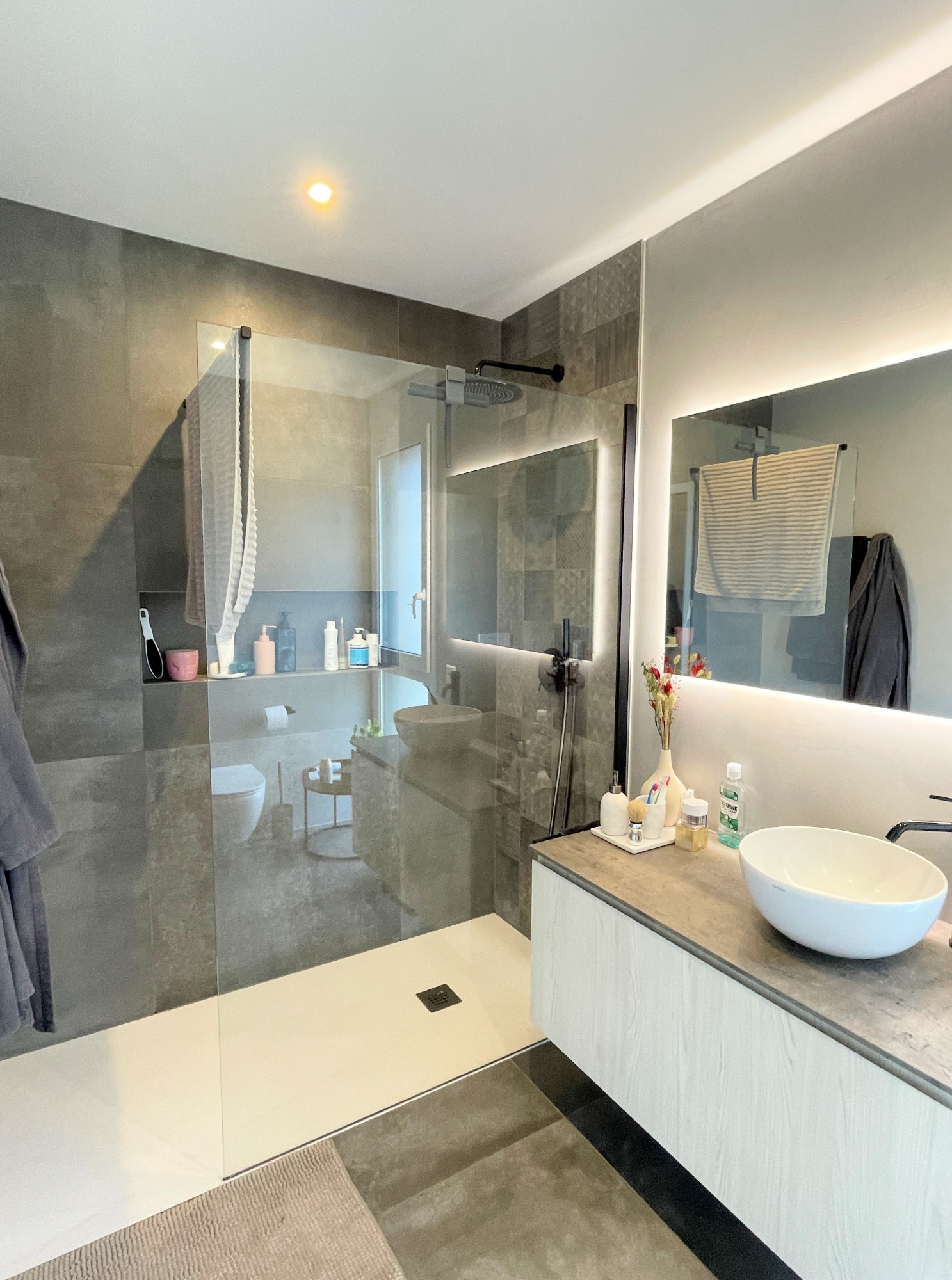 Modernes Badezimmer mit begehbarer Dusche und beleuchtetem Spiegel