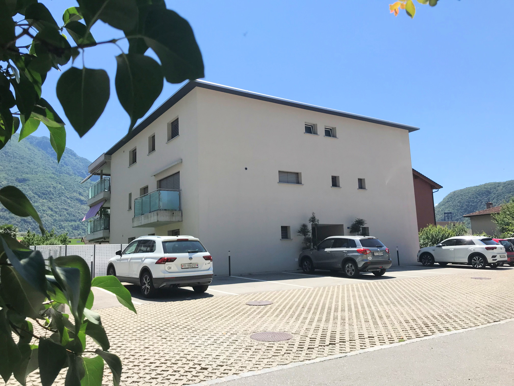 Modernes Mehrfamilienhaus mit Parkplatz vor Bergkulisse