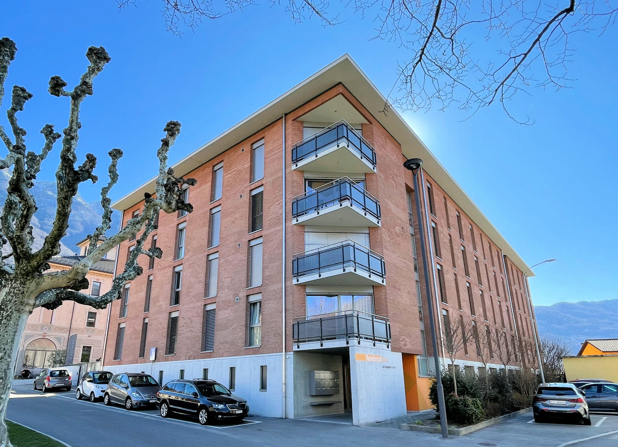 Mehrfamilienhaus mit Balkonen in sonniger Straßensituation