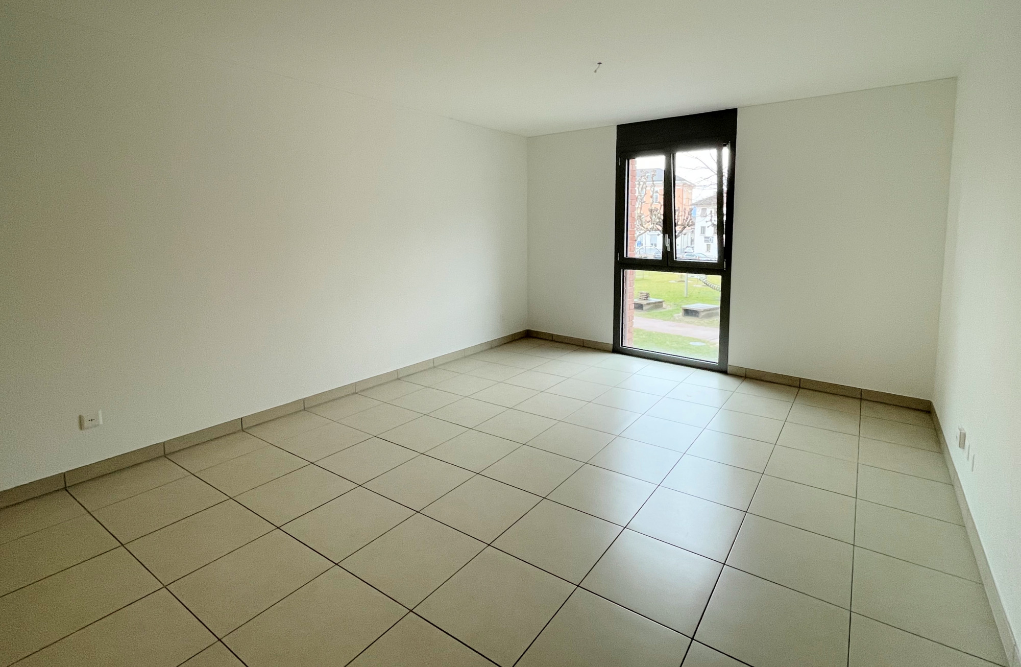 Leerer heller Raum mit Fliesenboden und großem Fenster