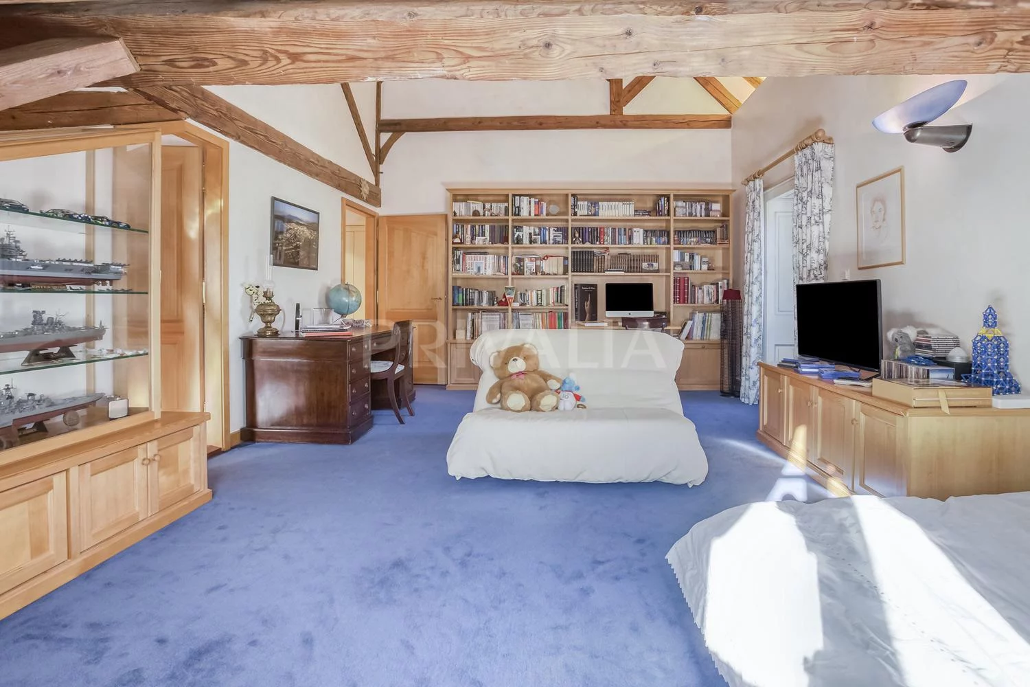 Helles Dachzimmer mit Holzdeckenbalken und Bibliothek