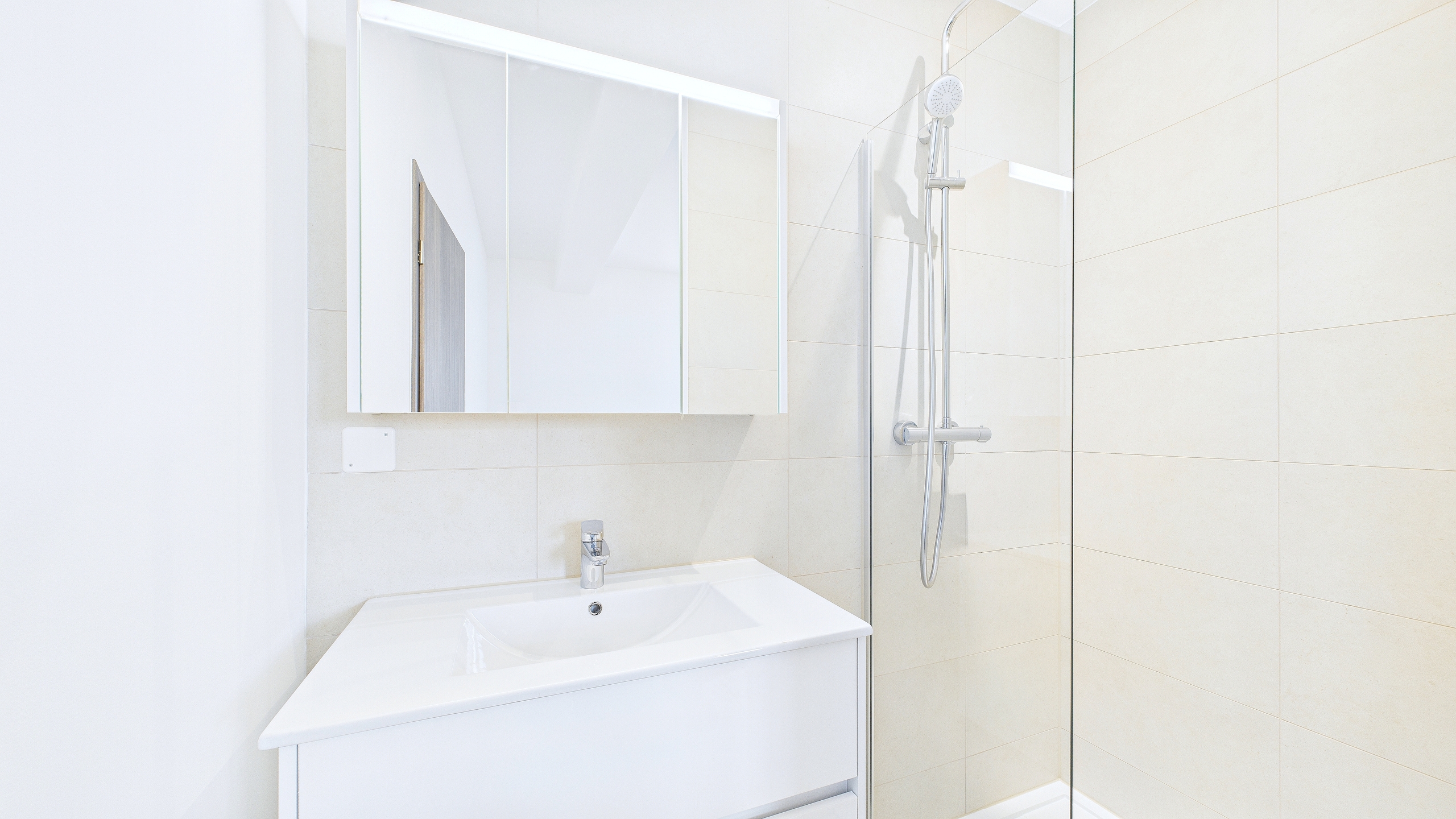 Modernes, helles Badezimmer mit Dusche und Waschbecken