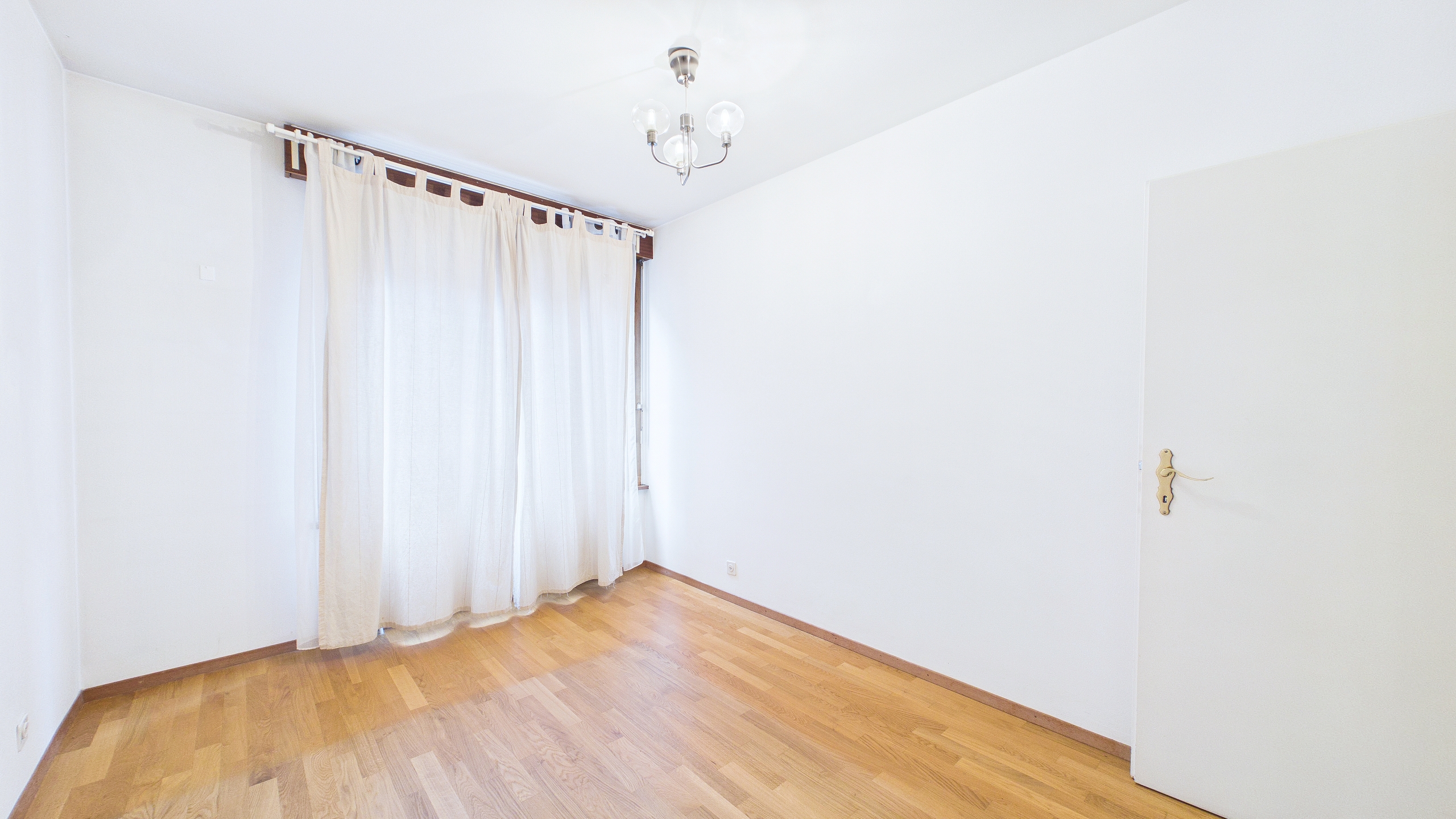 Heller leerer Raum mit Holzboden und Vorhängen