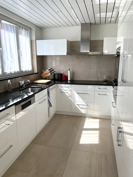 Moderne weiße Küche mit schwarzen Arbeitsflächen