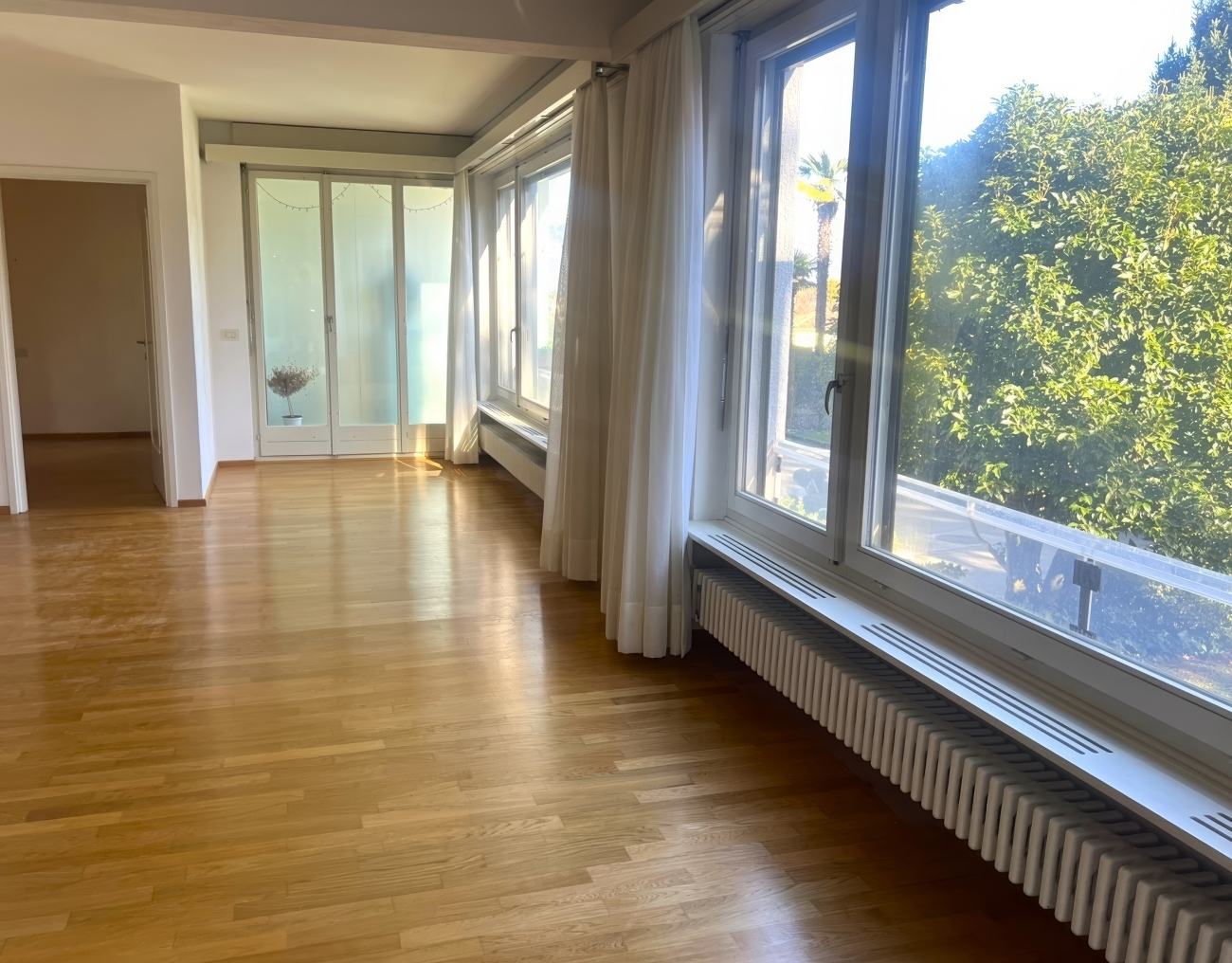 Heller Wohnraum mit großen Fenstern und Parkettboden
