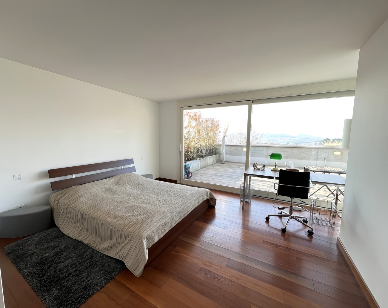 Schlafzimmer mit großer Glasfront und Arbeitsplatz