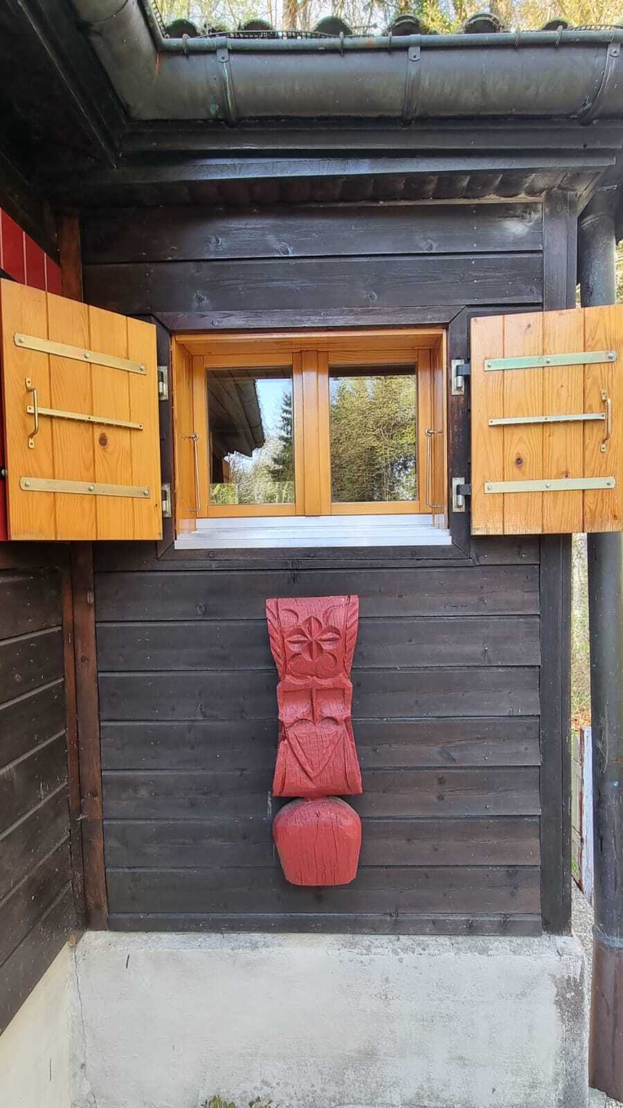 Holzfenster mit Läden an dunkler Holzfassade