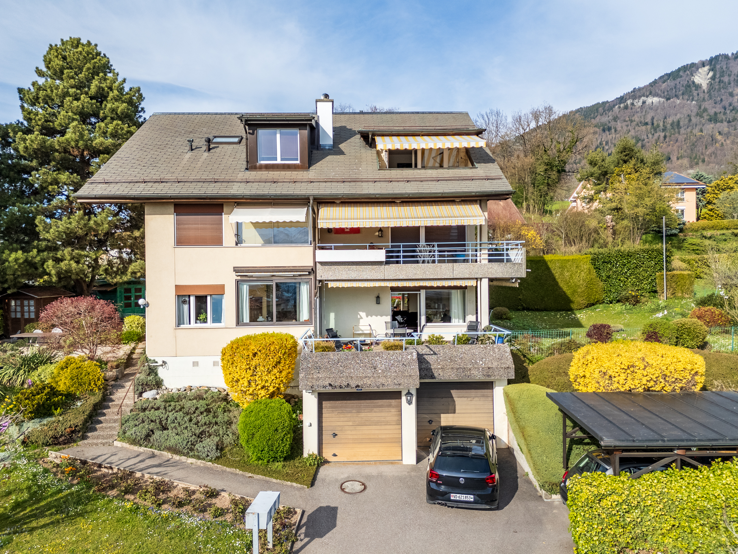 Freistehendes Haus mit Garten, Garagen und Bergen im Hintergrund