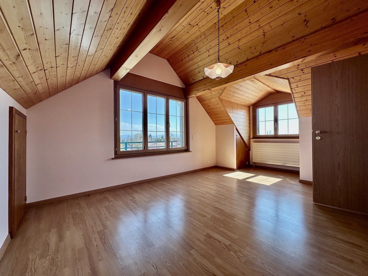 Dachgeschossraum mit Holzdecke und Blick nach draußen
