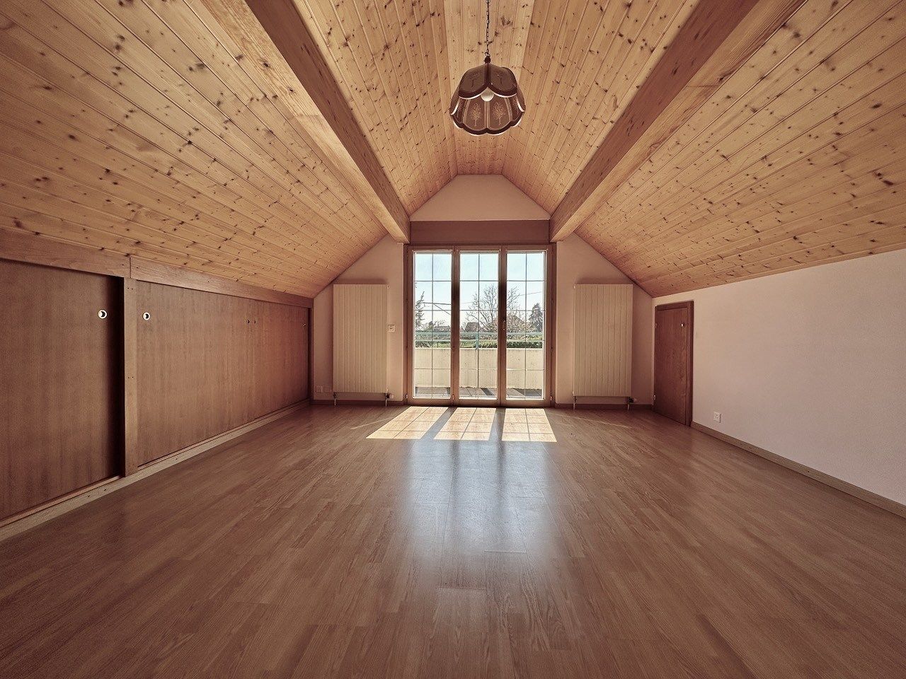 Dachgeschossraum mit Holzdecke und Balkonfenster