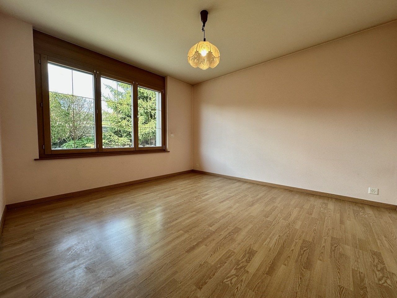 Leerer Wohnraum mit Holzfenster und Parkettboden