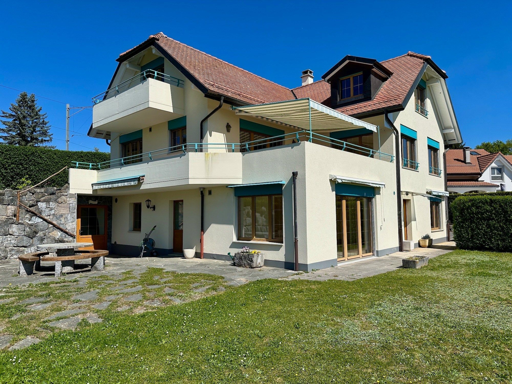 Außenansicht eines gepflegten Einfamilienhauses mit Balkonen und Garten