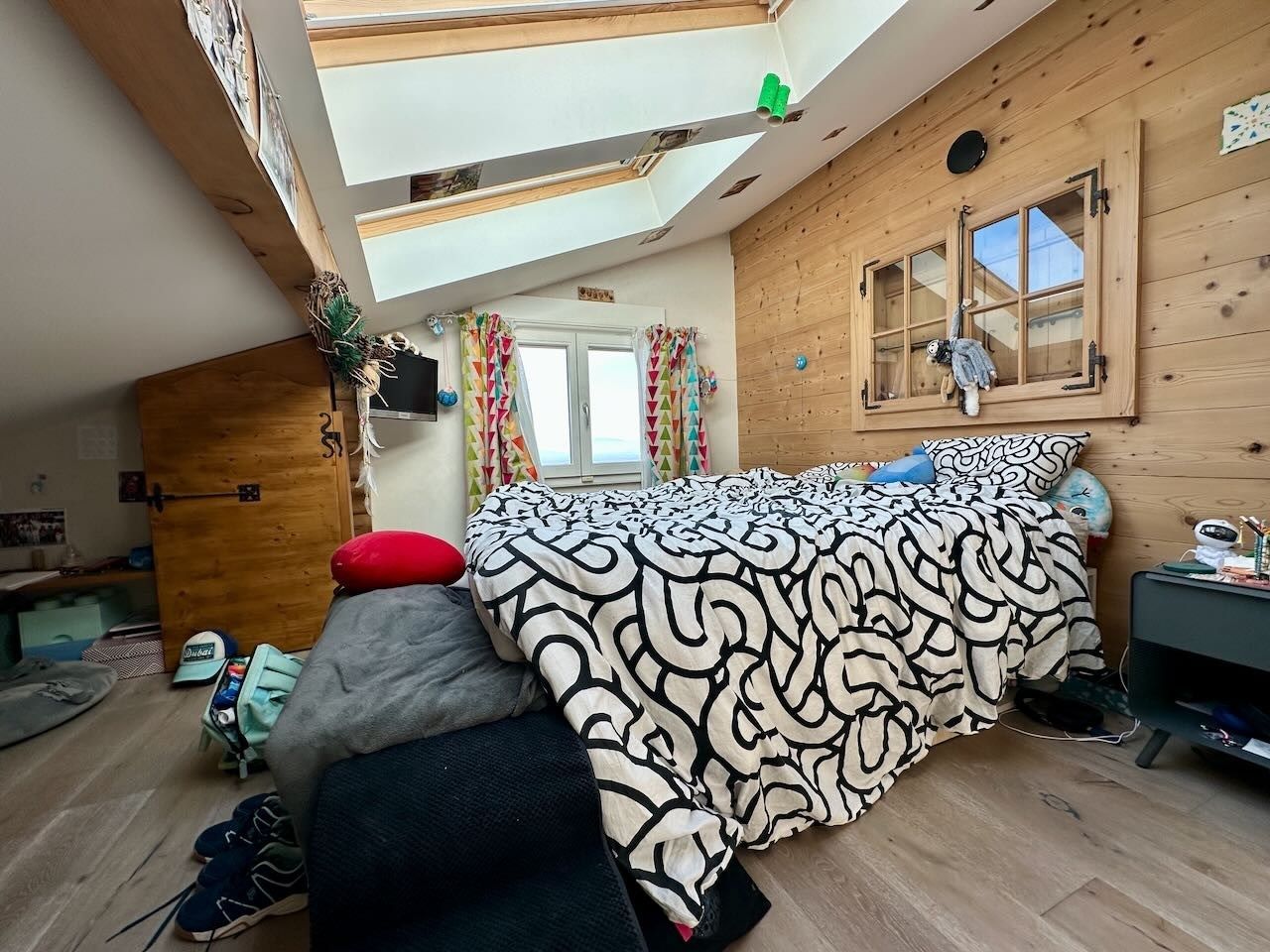 Gemütliches Dachzimmer mit Bett und Holzvertäfelung