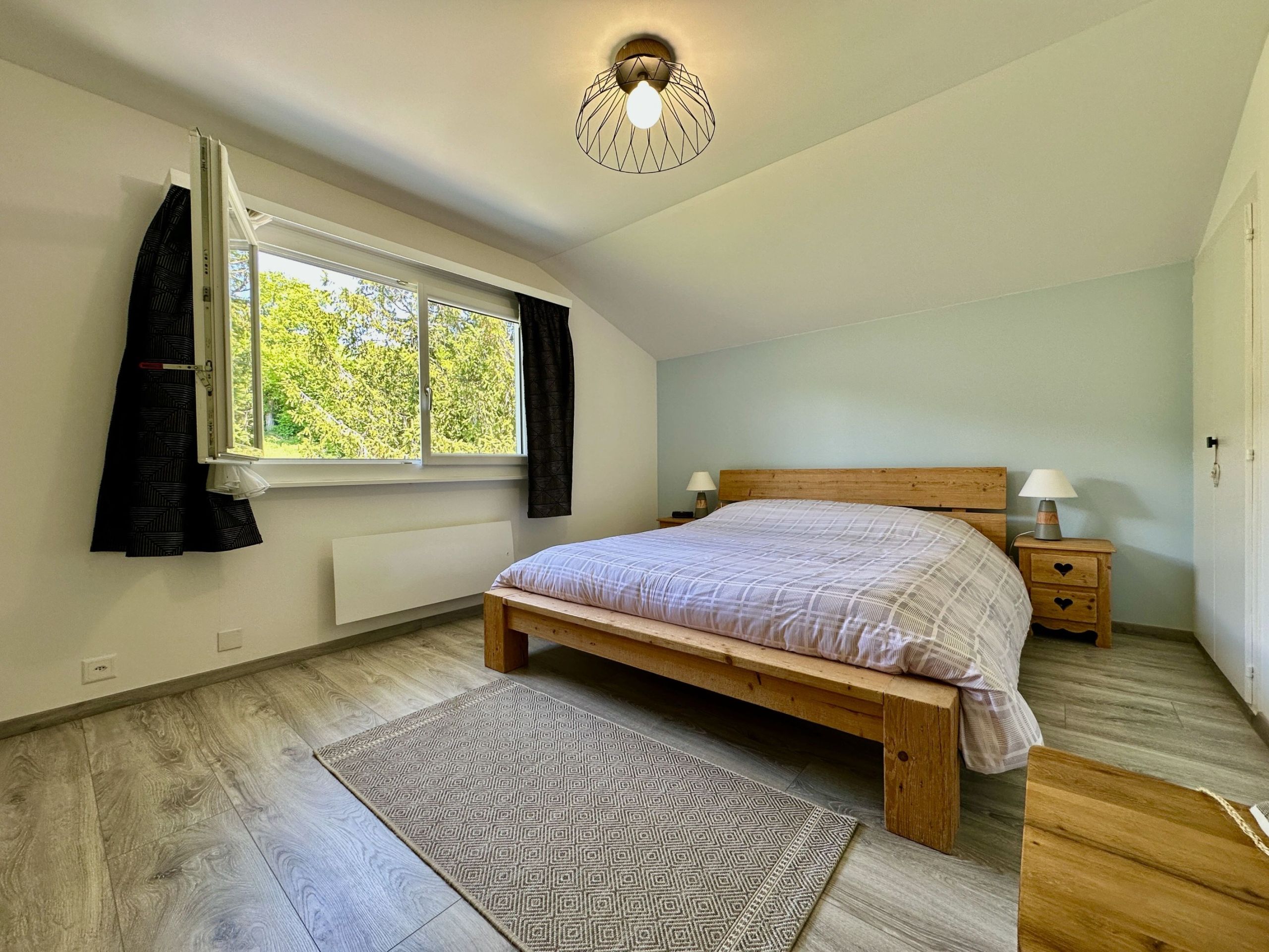 Helles Schlafzimmer mit Holzbett und großem Fenster