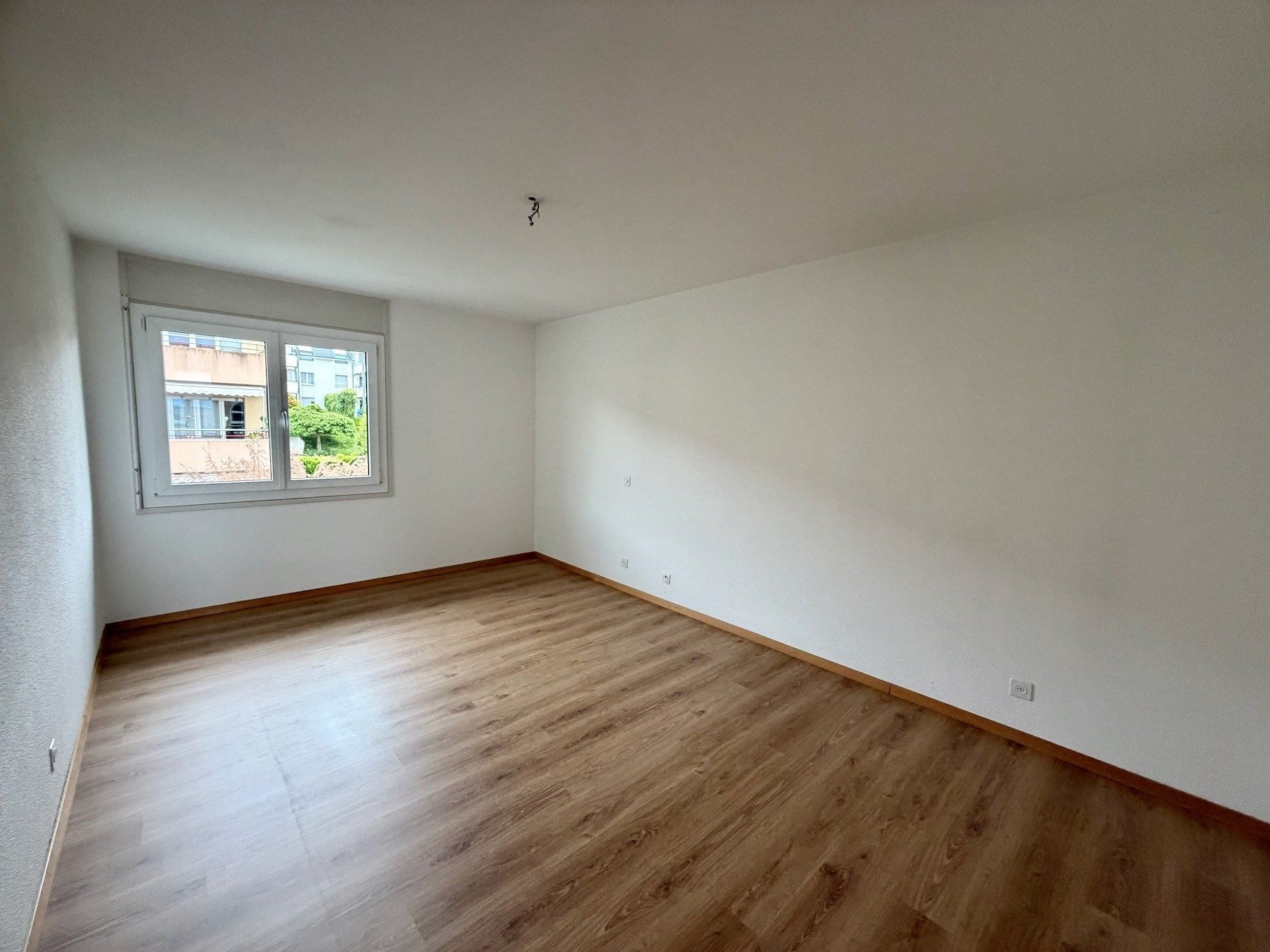 Leeres Zimmer mit Holzoptikboden und Fenster