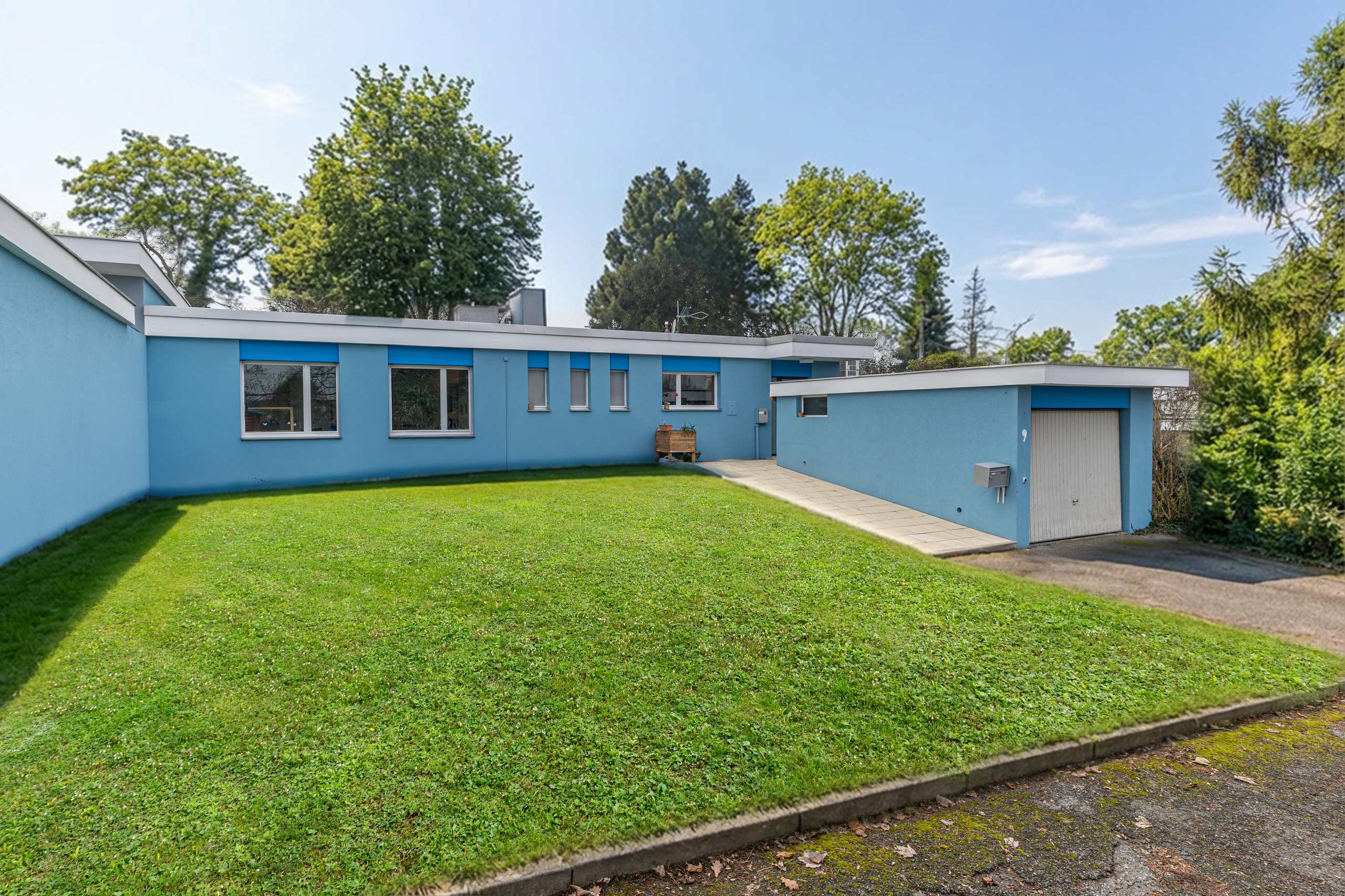 Blaue Flachbau-Ansicht mit Garten und Garage