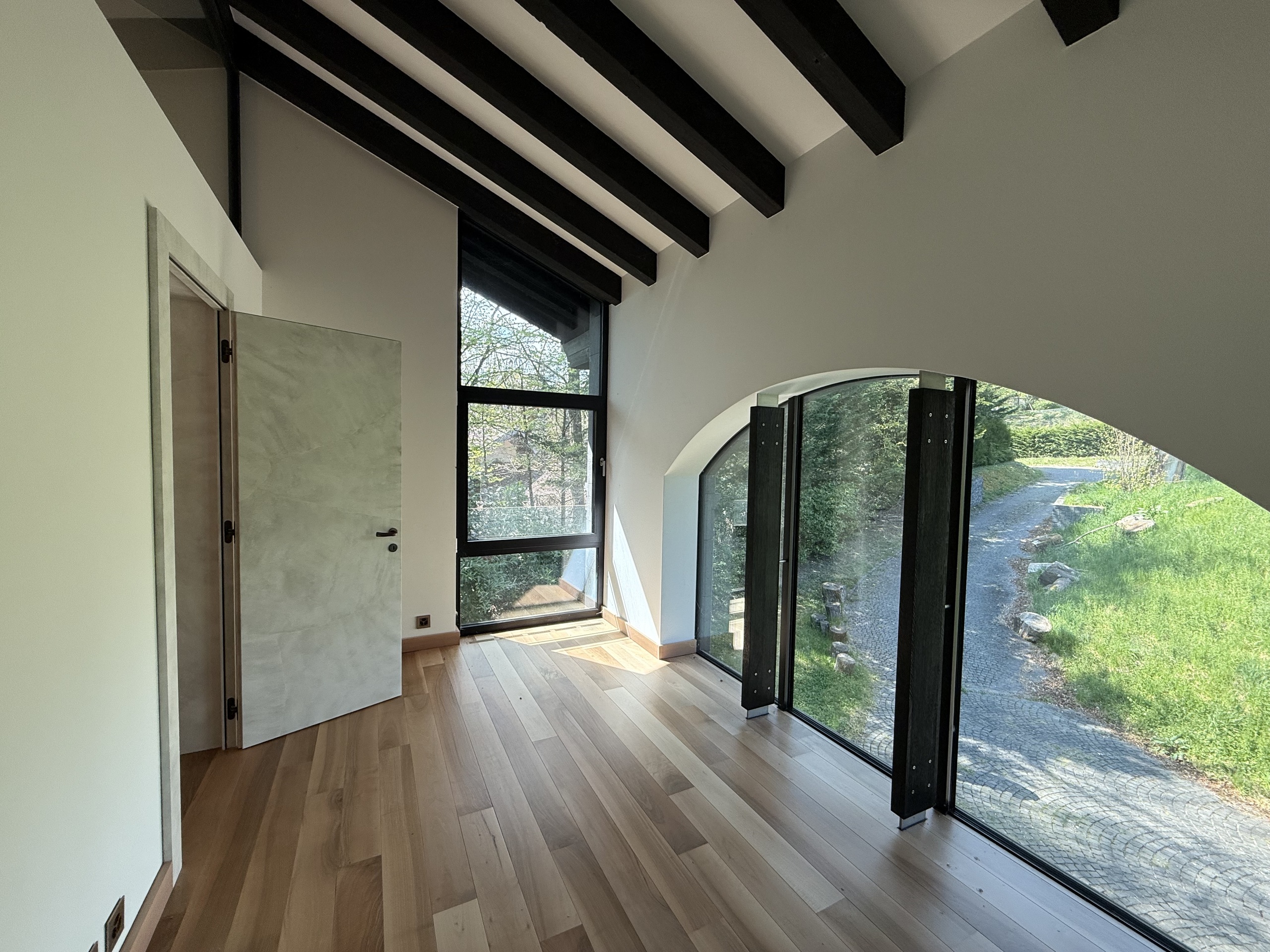 Lichtdurchfluteter Raum mit hohen Fenstern und Holzdecke