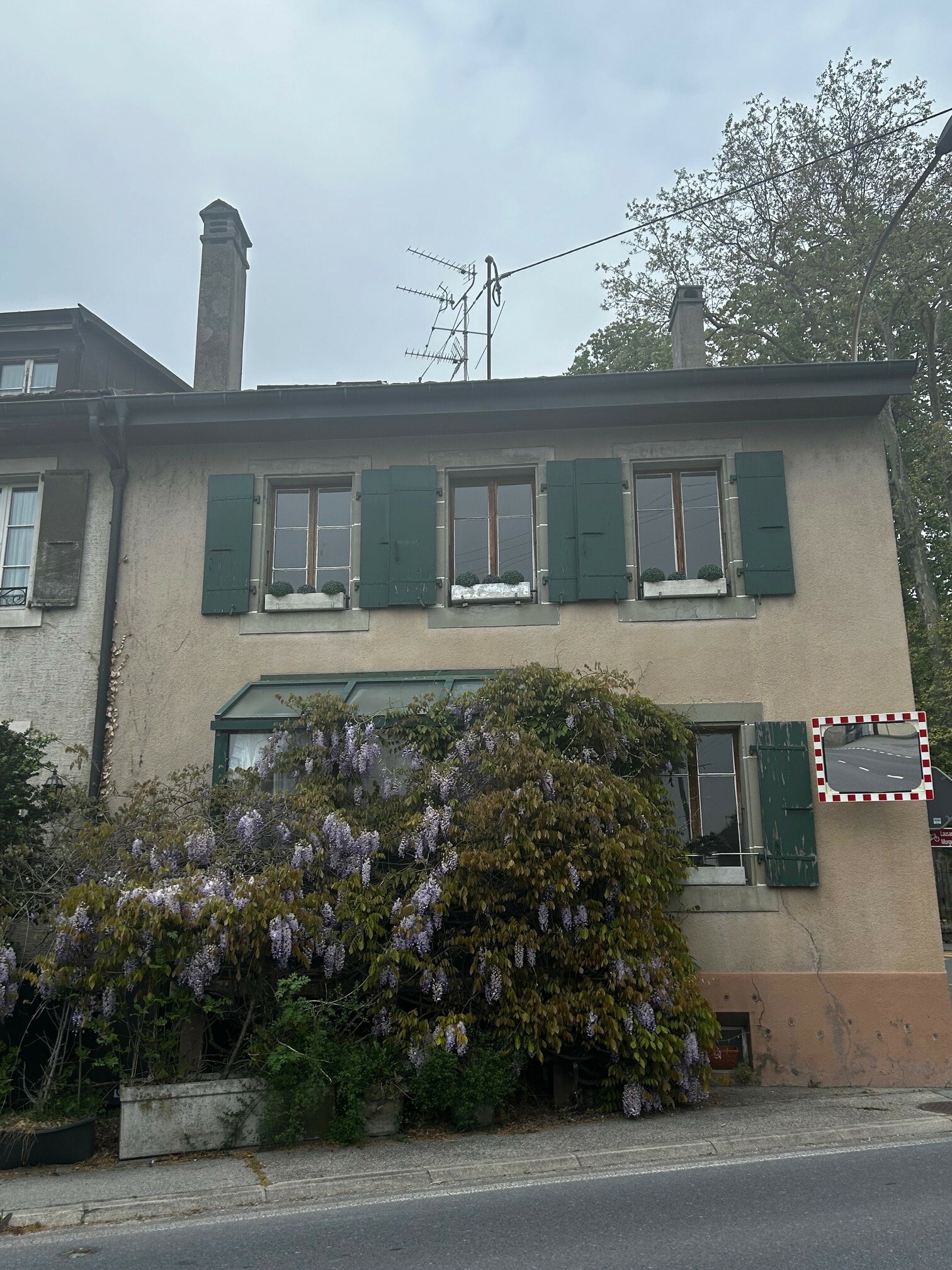 Straßenansicht eines zweigeschossigen Hauses mit grünen Fensterläden