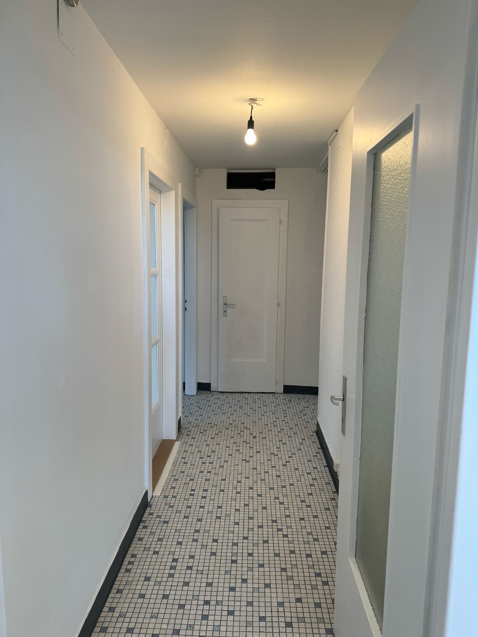 Flur mit Mosaikboden und weißen Türen
