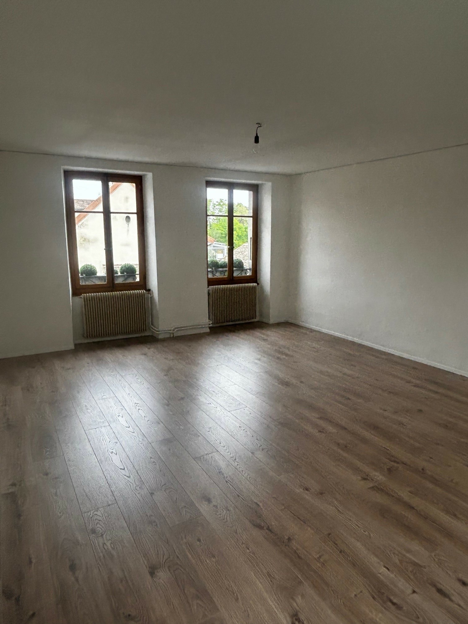 Leerer Raum mit Parkett und zwei Fenstern