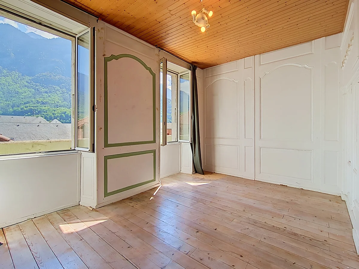 Heller Altbau-Raum mit Holzdielen und Bergblick