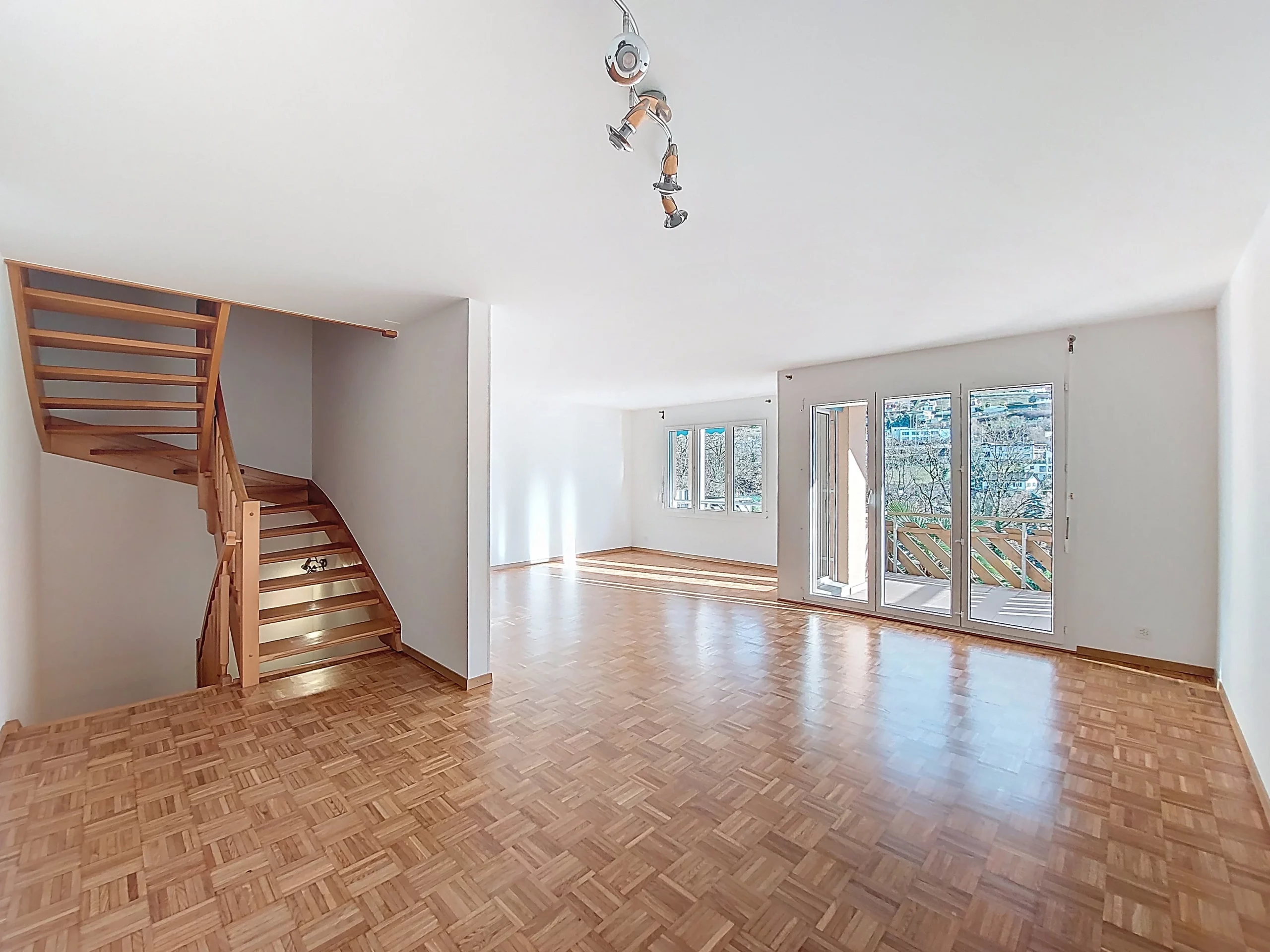 Heller Wohnraum mit Holztreppe und Balkon