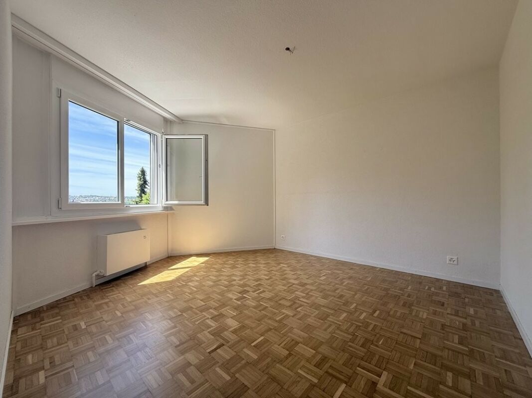 Heller leerer Raum mit Parkett und geöffnetem Fenster