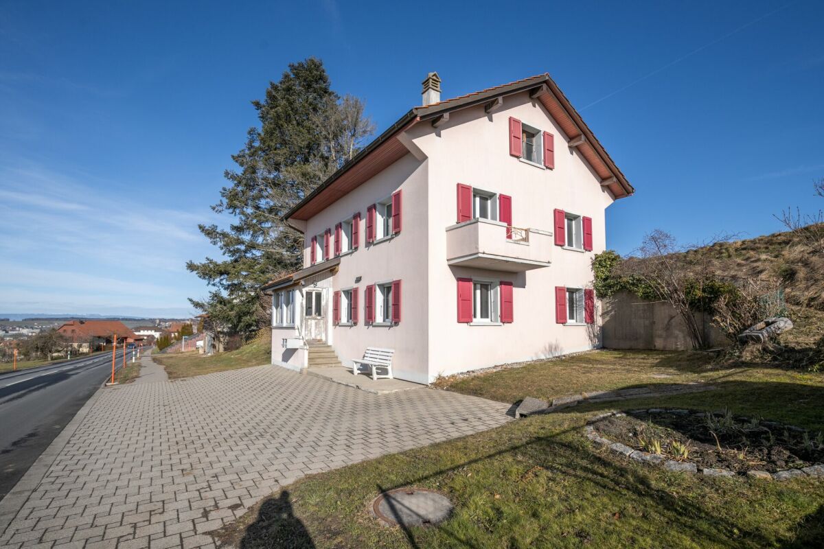 Wohnhaus mit heller Fassade und roten Fensterläden