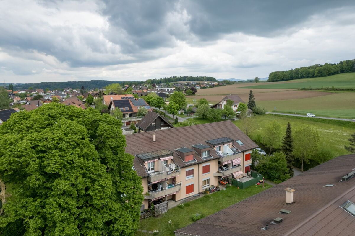 Luftaufnahme eines Wohngebiets mit Mehrfamilienhäusern und Feldern