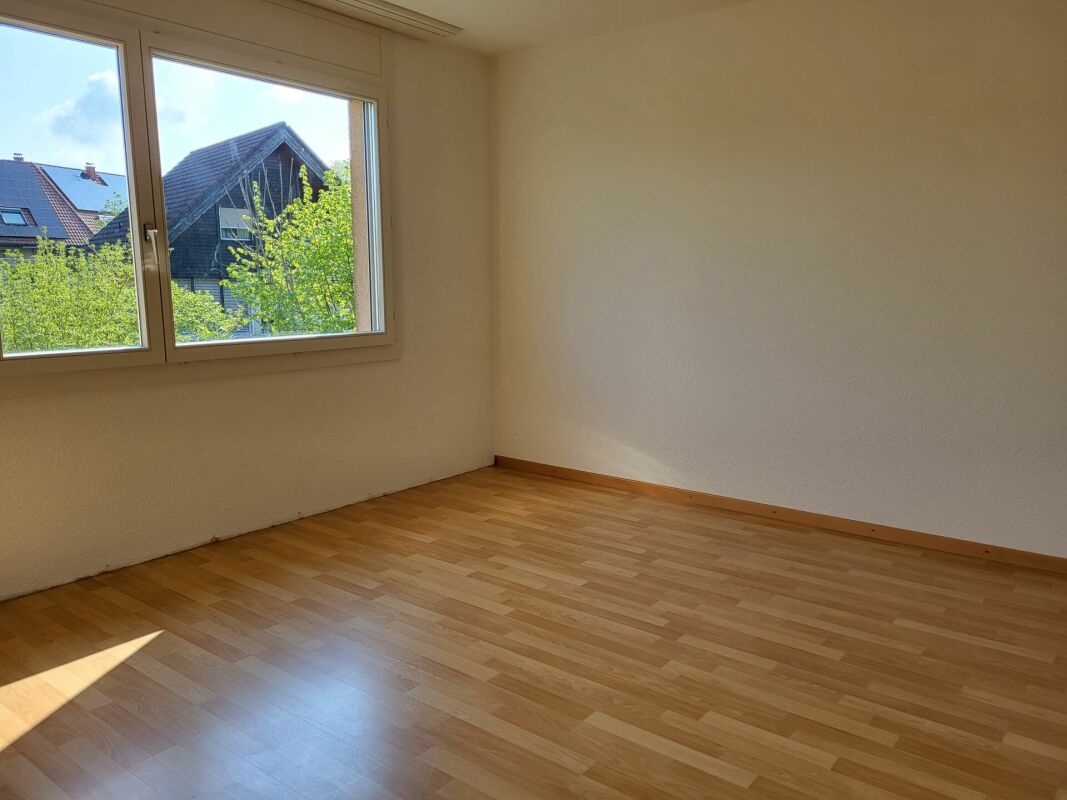Leerer Wohnraum mit Holzfußboden und großem Fenster