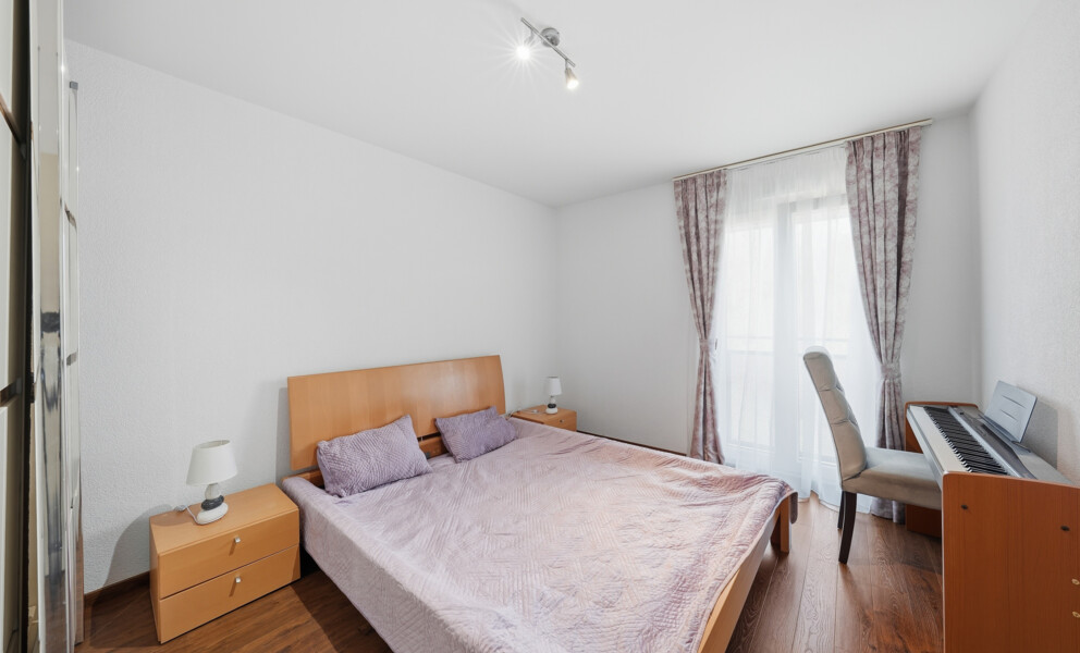 Helles Schlafzimmer mit Doppelbett und Klavier