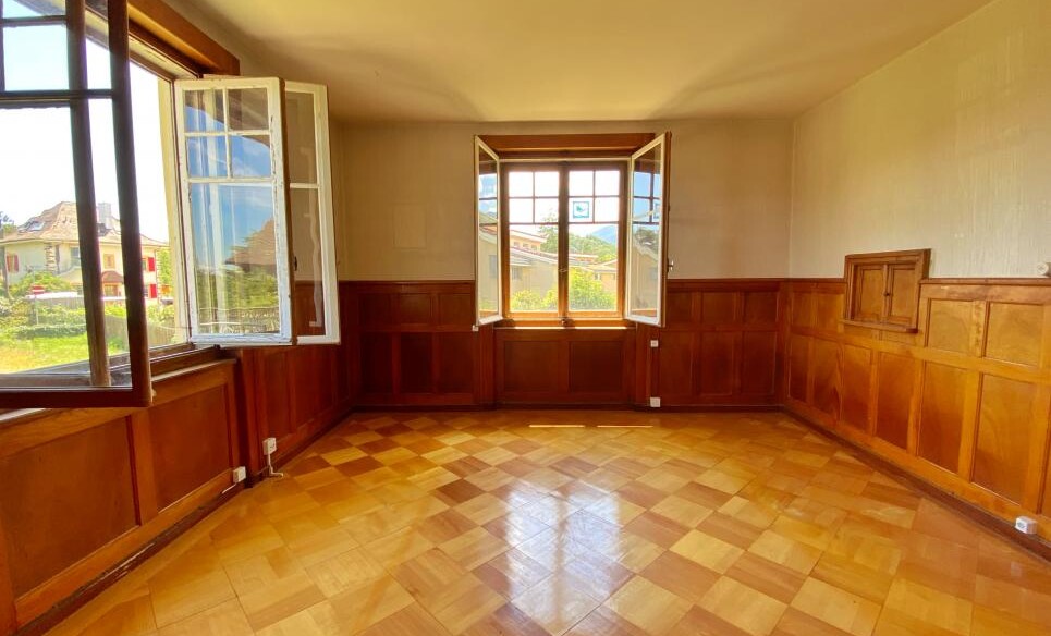 Heller leerer Raum mit Holzvertäfelung und geöffneten Fenstern