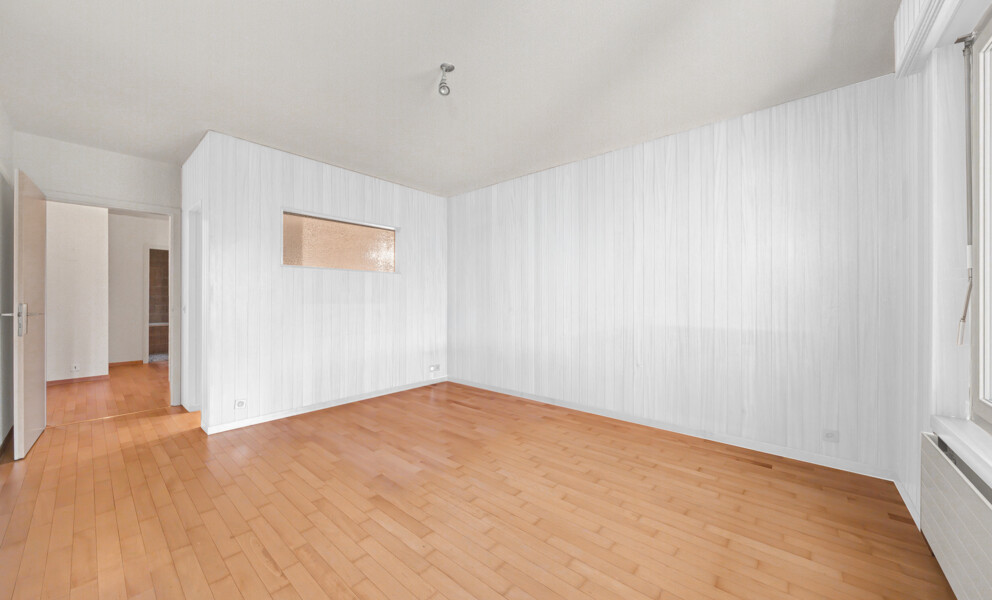 Leerer Wohnraum mit Holzparkett und weißen Wänden