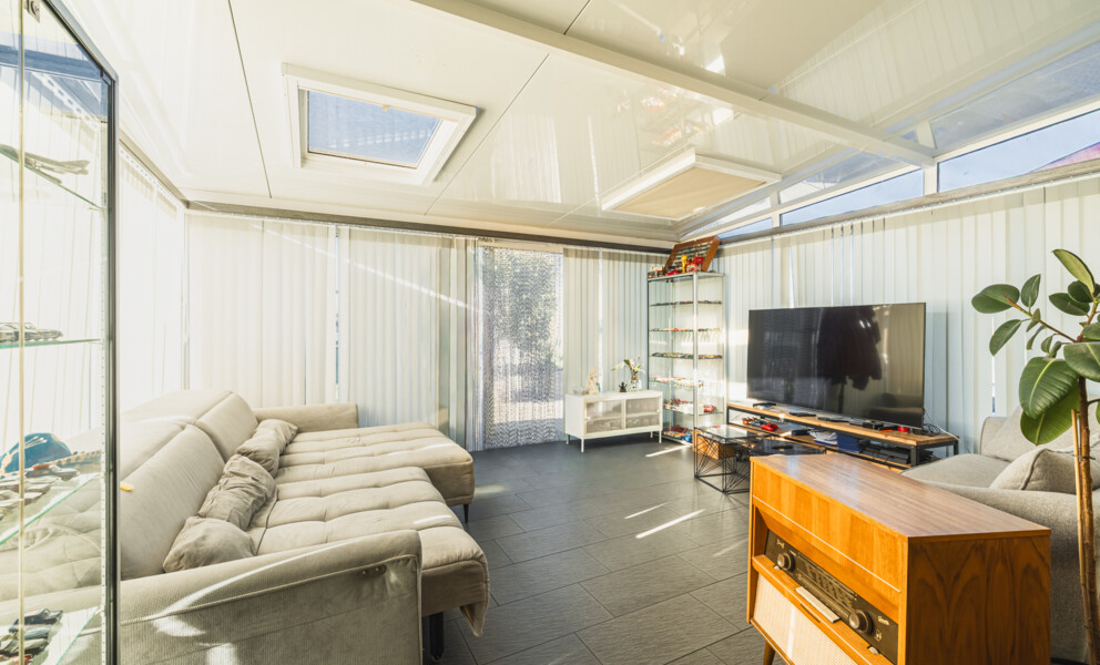 Verglaster Wohnbereich mit Sofa und TV