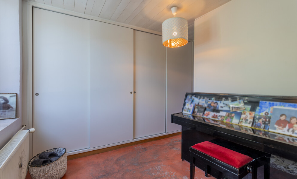 Helles Zimmer mit weißen Schrankfronten und Klavier