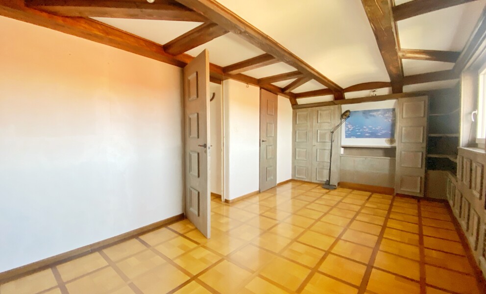 Dachgeschosszimmer mit Holzbalken und Schrankwand