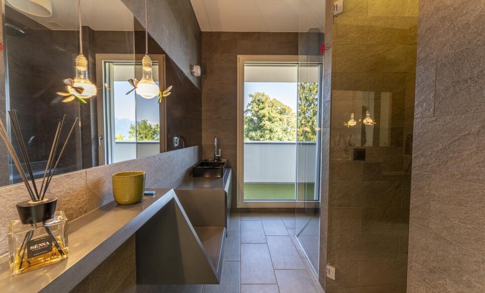 Modernes Badezimmer mit dunkler Natursteinoptik und bodentiefer Fensterfront