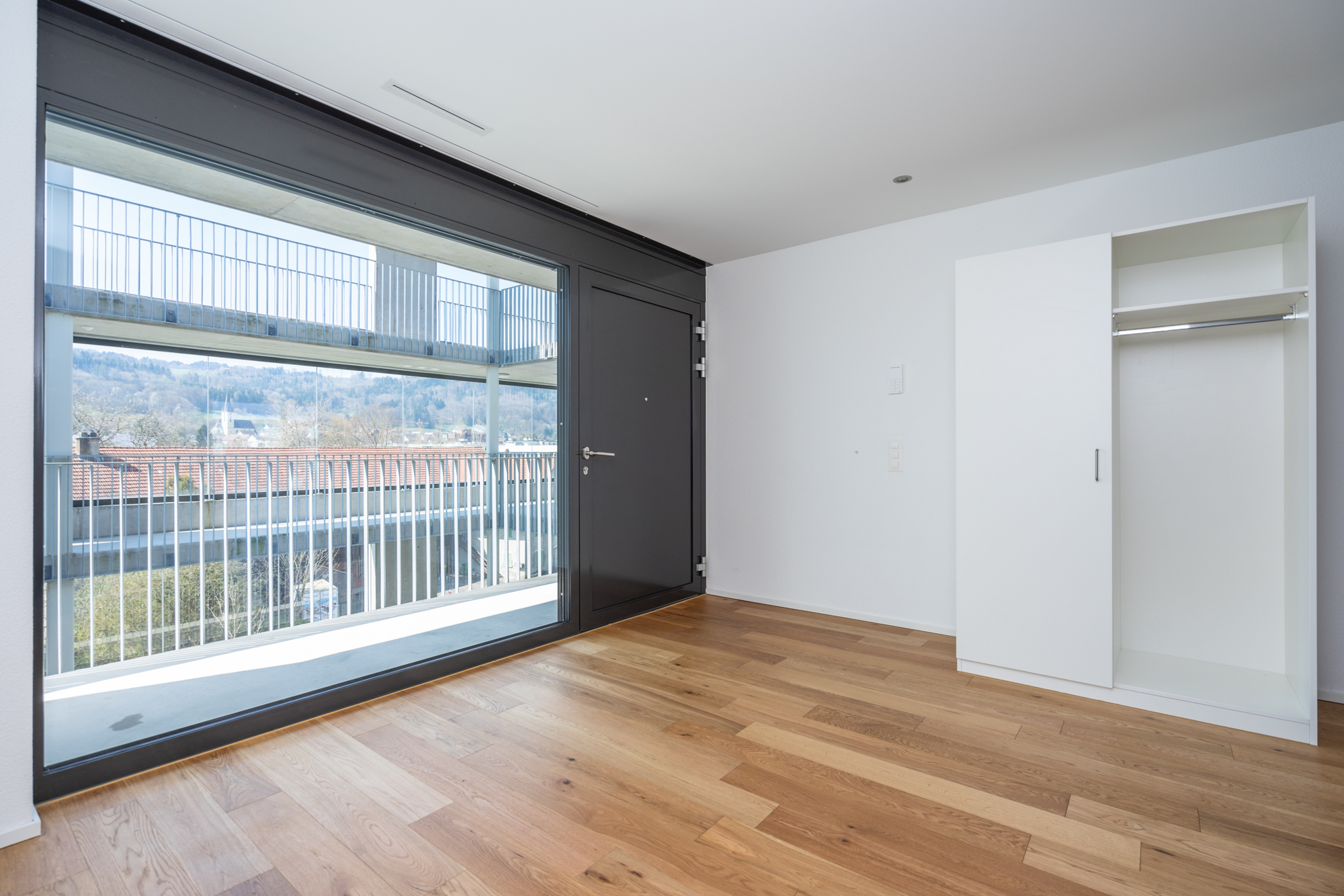 Helles Schlafzimmer mit großem Fenster und Einbauschrank