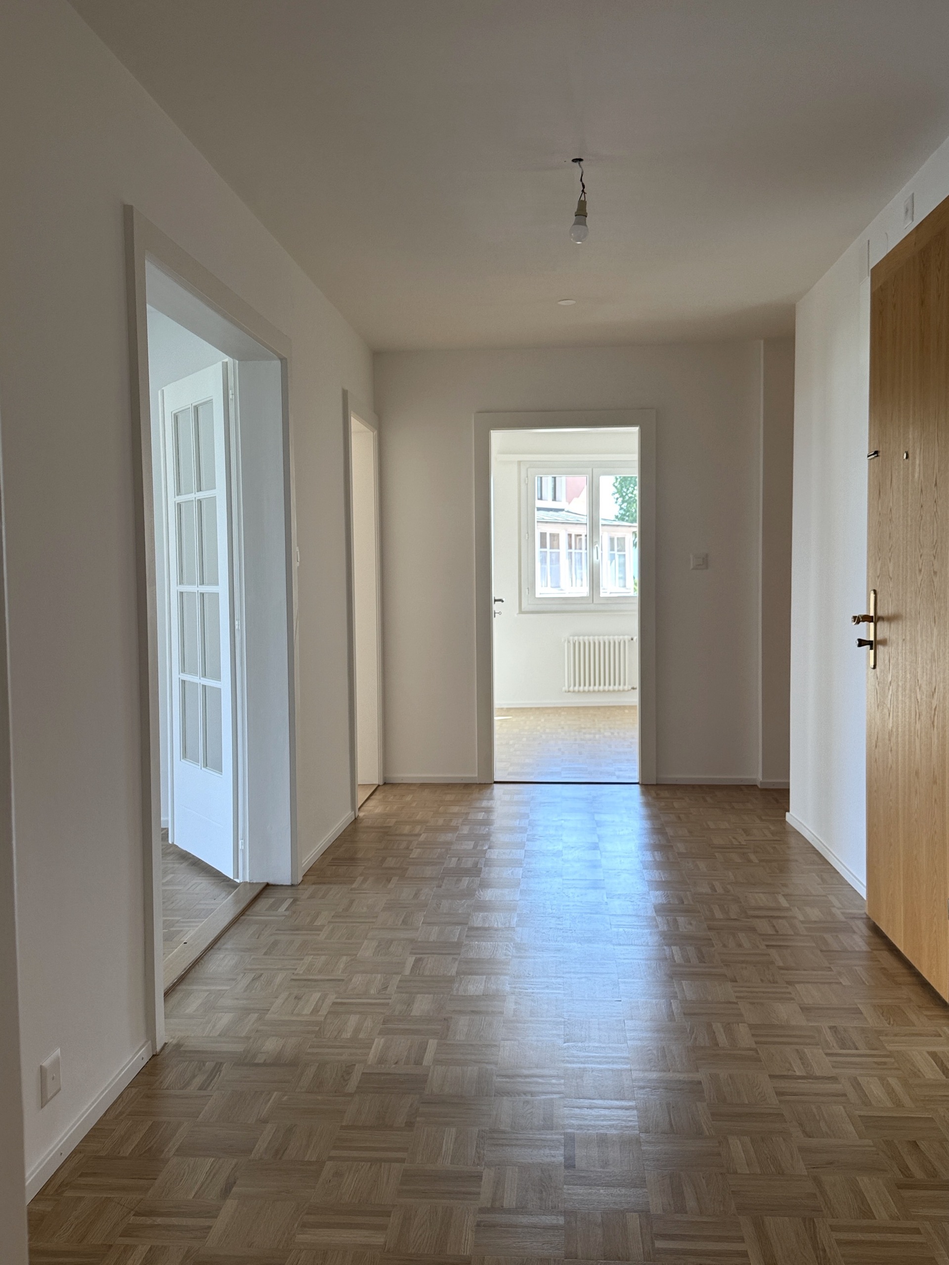 Heller Flur mit Parkettboden und angrenzenden Räumen