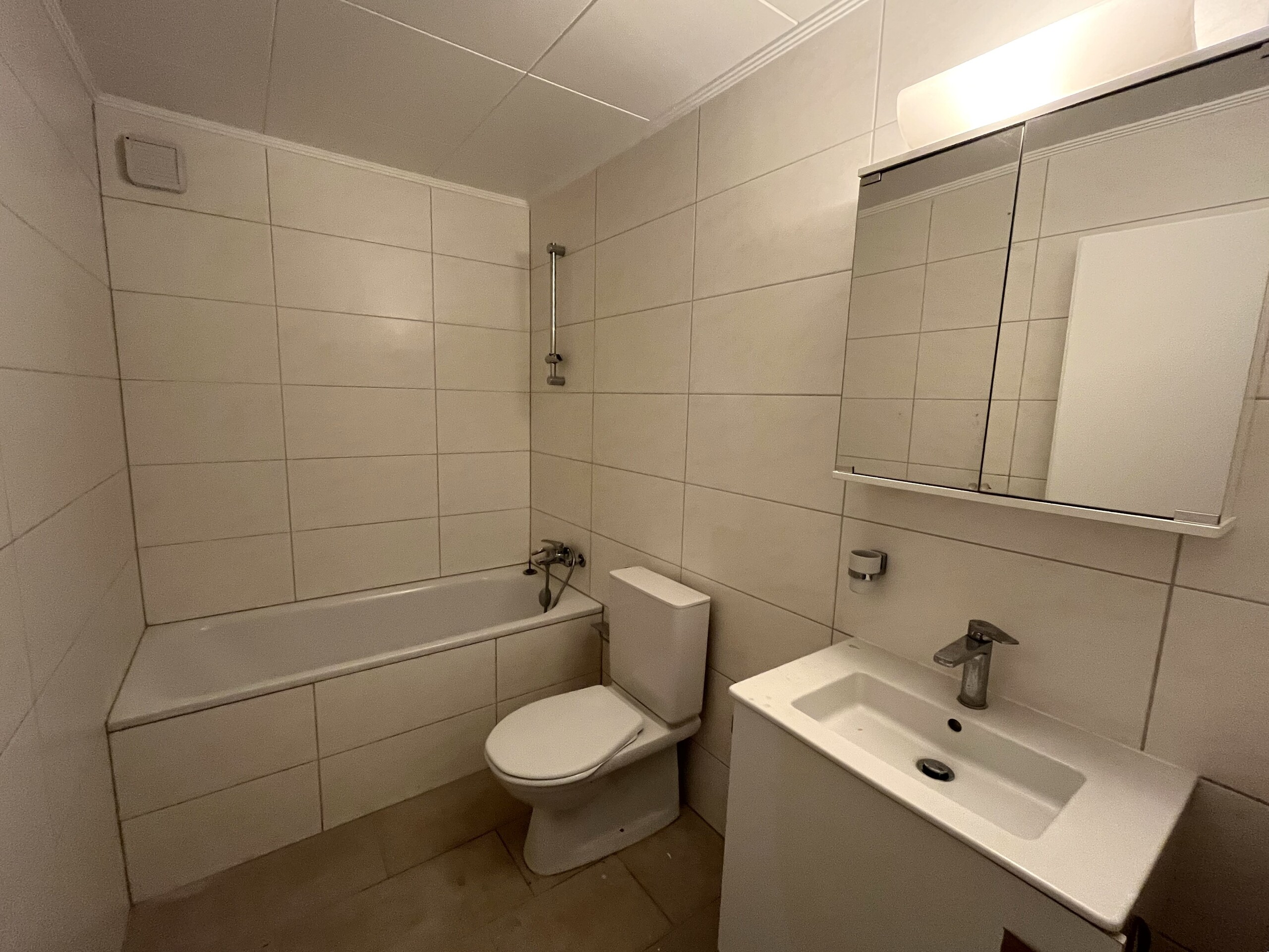 Kleines, schlichtes Badezimmer mit Wanne, WC und Waschtisch