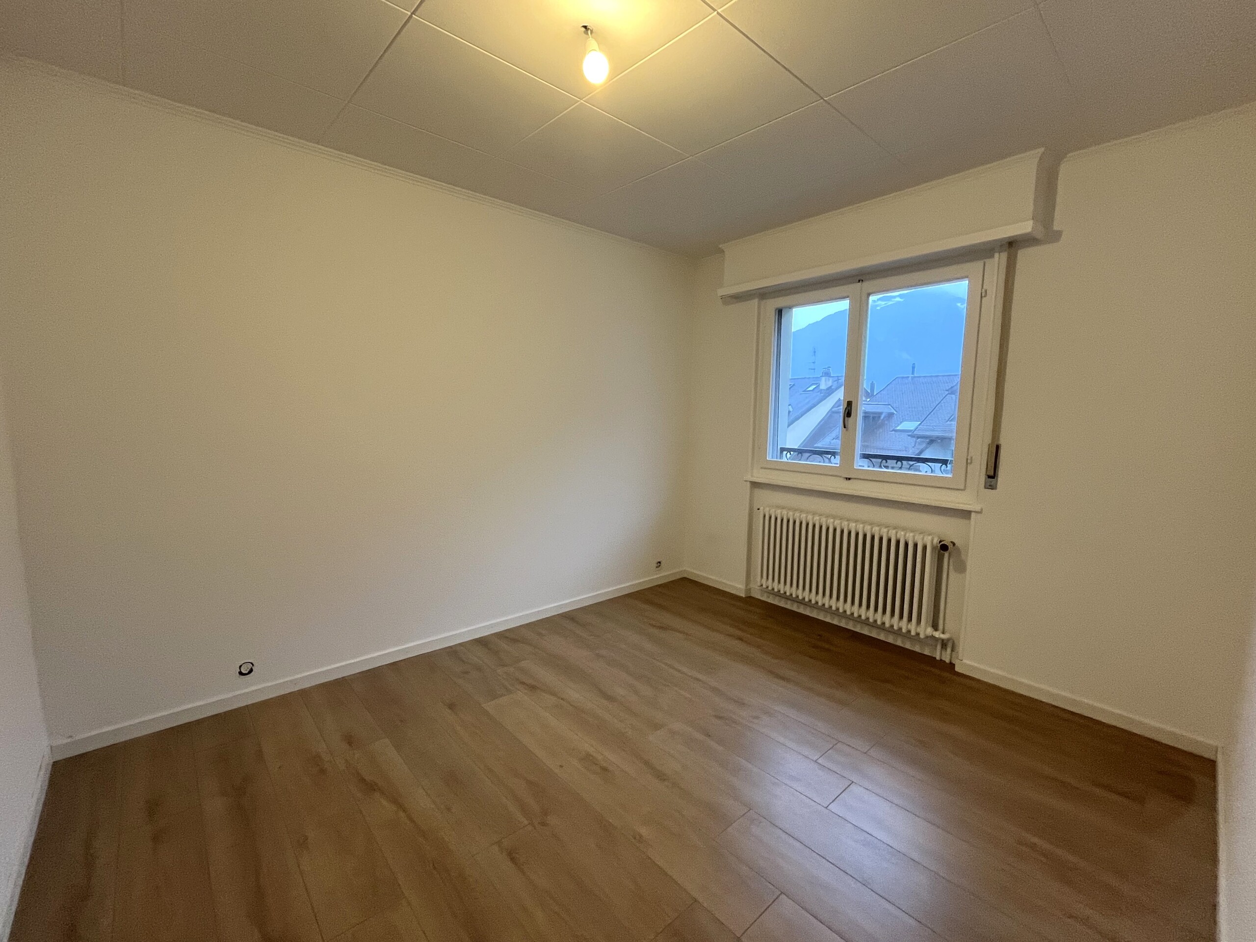 Leerer Wohnraum mit Fenster und Heizkörper