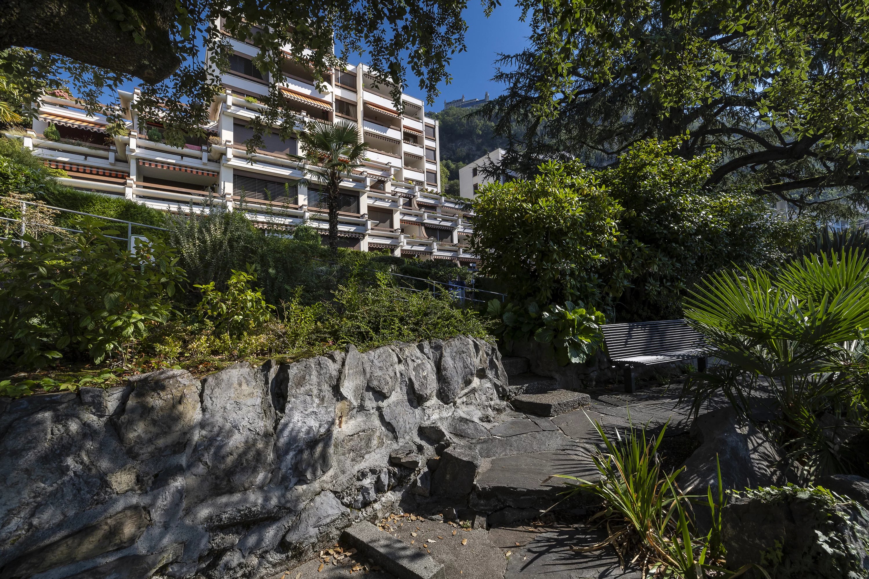 Üppige Gartenanlage vor einem terrassenförmigen Wohngebäude