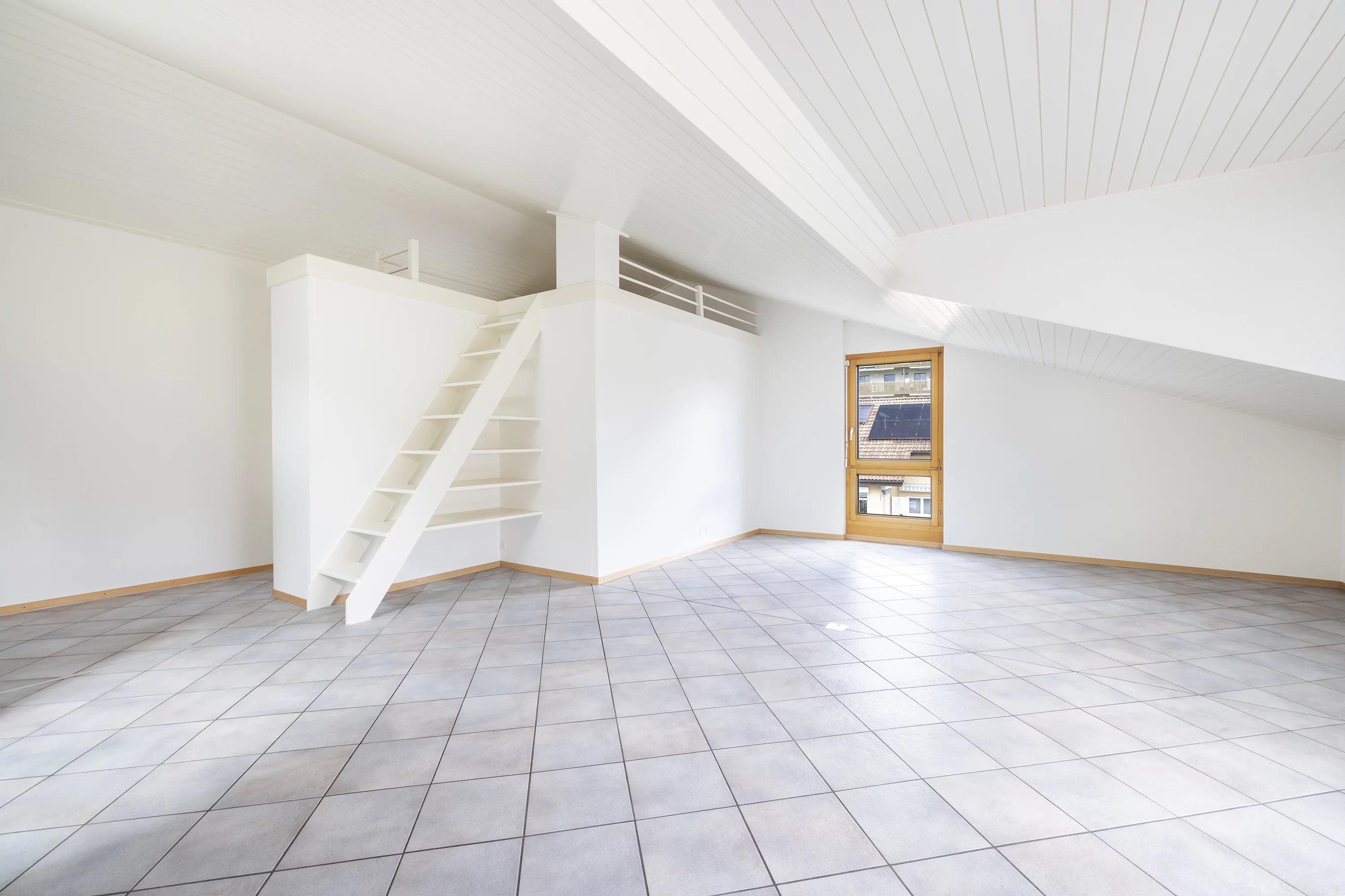 Heller leerer Dachbodenraum mit Leiter und Dachfenster