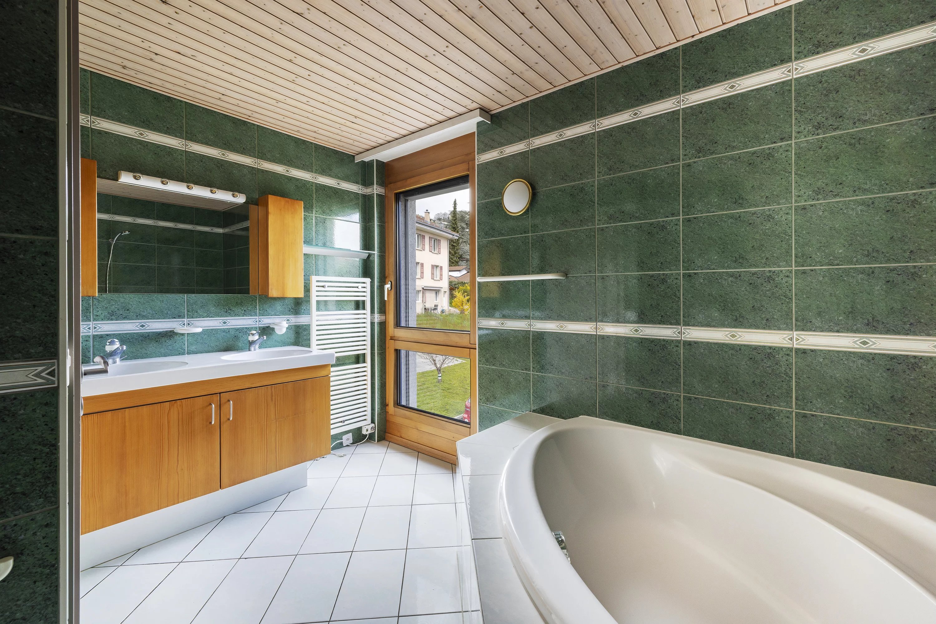 Badezimmer mit Badewanne und grün gefliesten Wänden