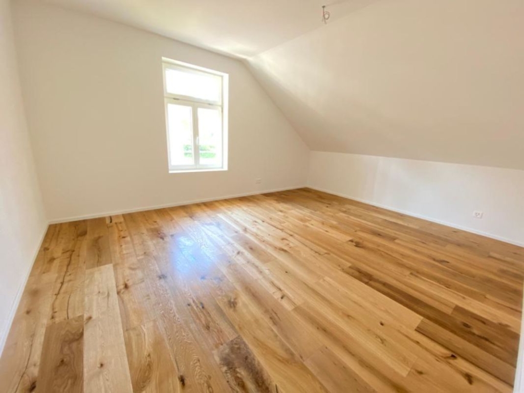 Leerer Dachraum mit Fenster und Holzboden