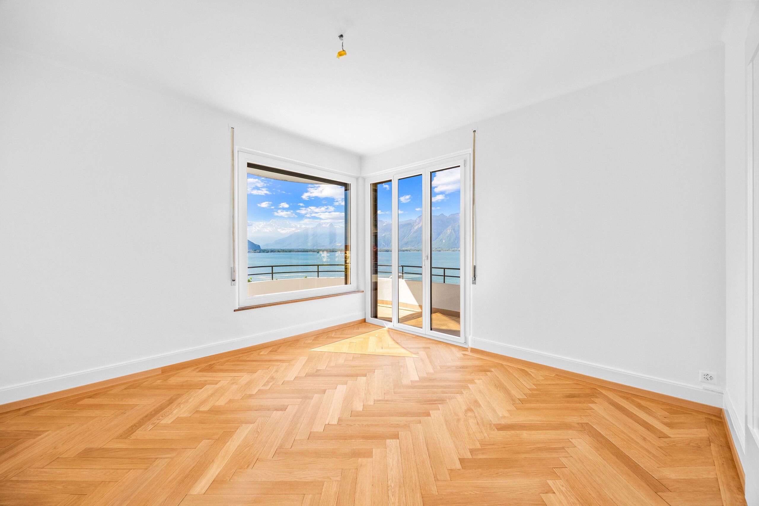 Heller leerer Raum mit Seeblick und Bergpanorama