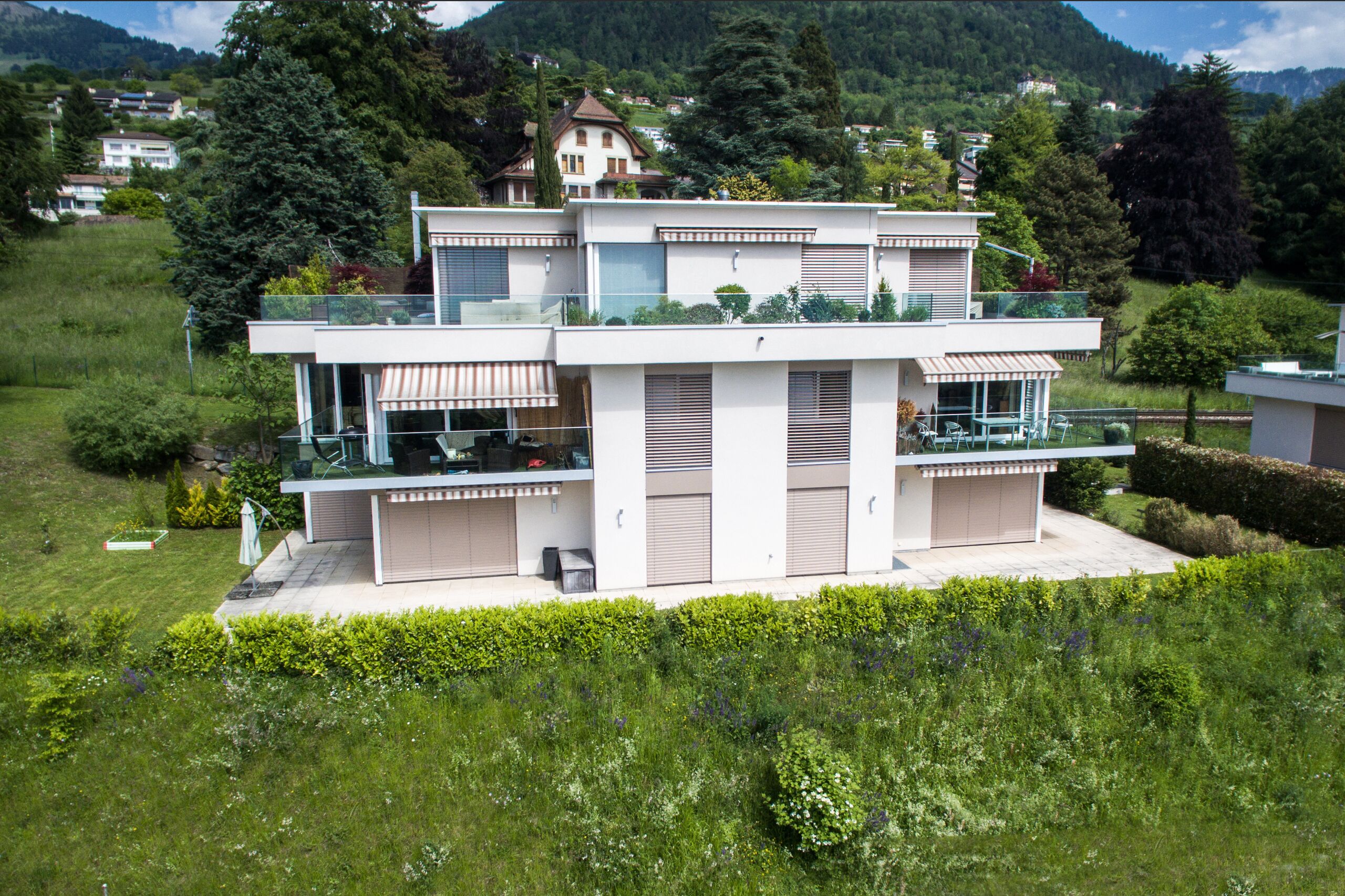 Modernes Haus mit großzügigen Terrassen in grüner Hügellandschaft