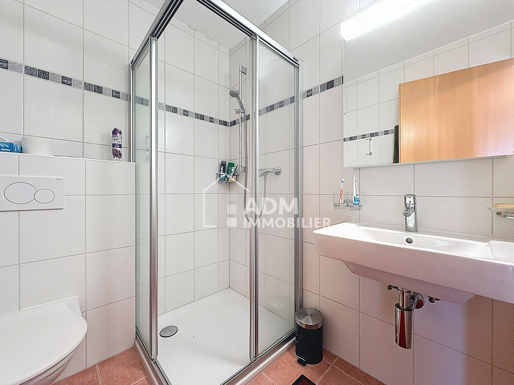 Kleines weiß gefliestes Badezimmer mit Dusche und Waschbecken