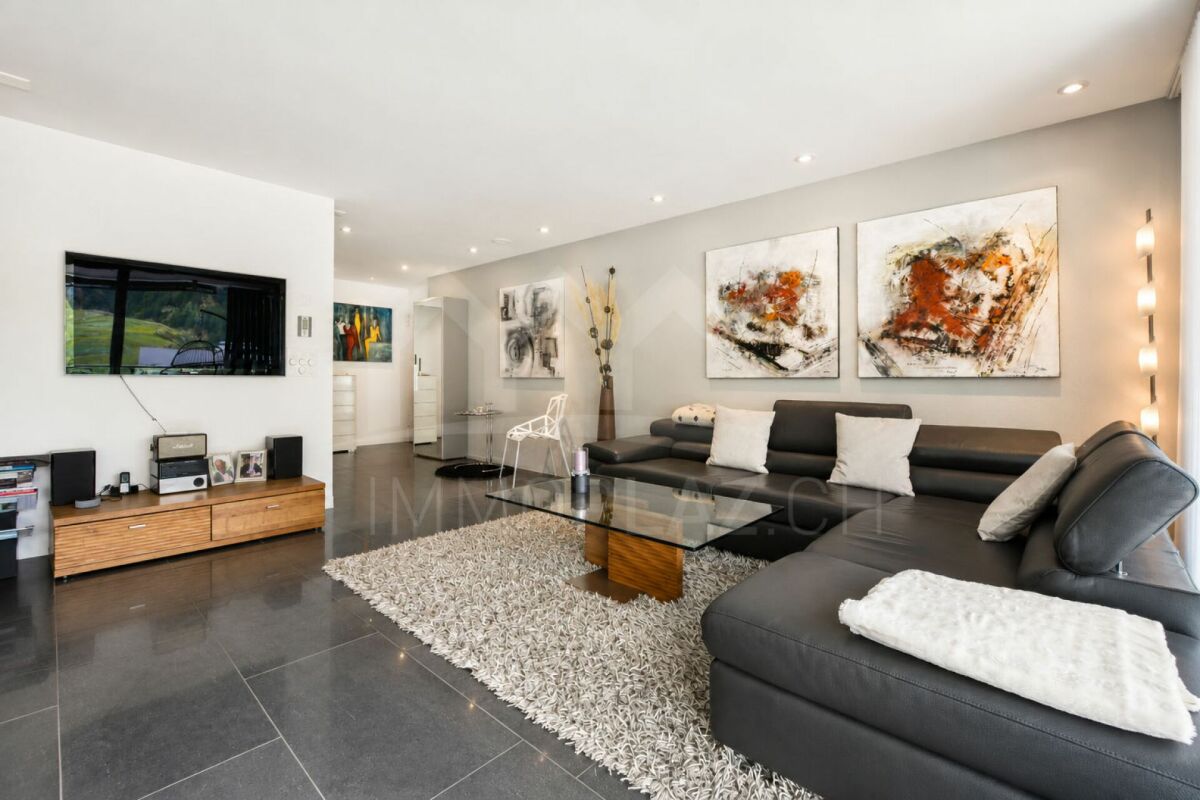 Modernes Wohnzimmer mit dunkler Eckcouch und Kunst