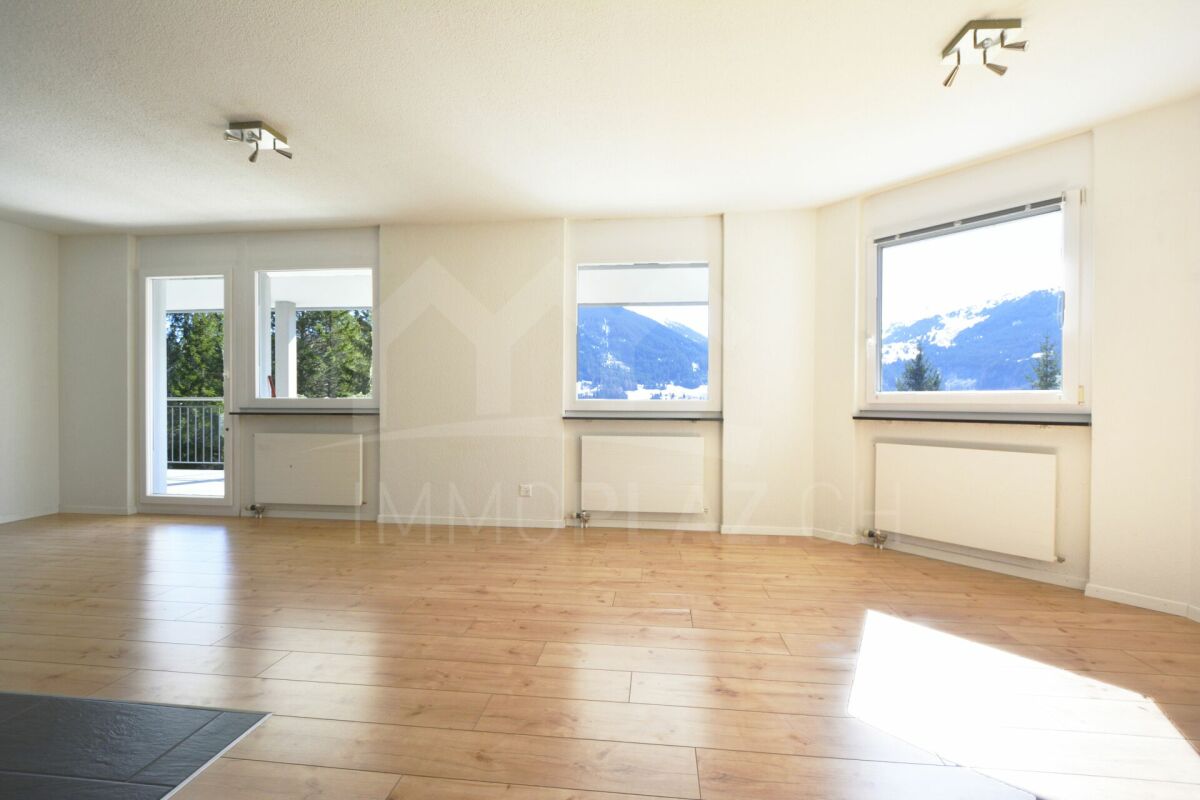 Heller, leerer Wohnraum mit großen Fenstern und Bergblick